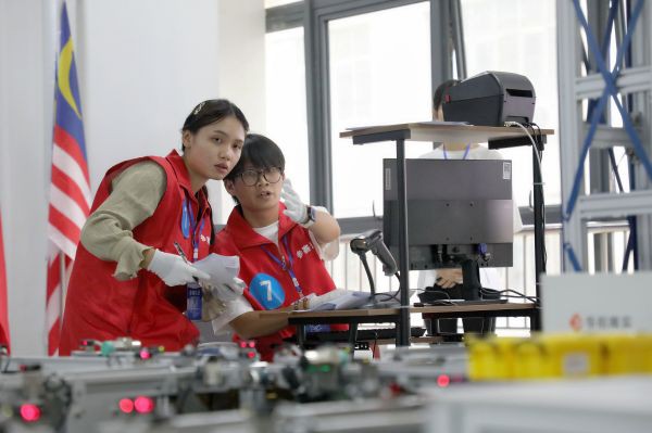 5.在2023中国—东盟智慧物流国际邀请赛现场，一名来自东盟国家的参赛选手在比赛过程中遭遇难题，中国学生正在耐心为她指引.jpg